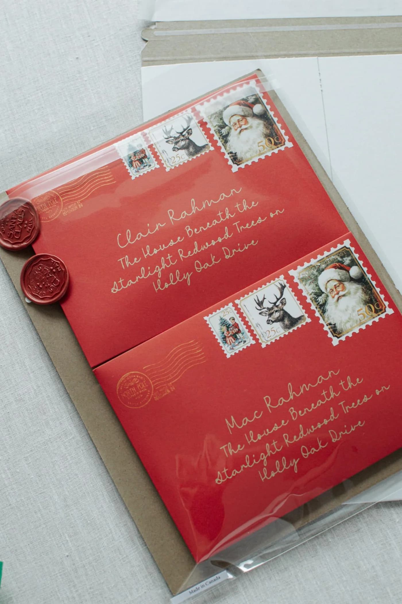Two individually addressed red envelopes with gold calligraphy and wax seals, in clear sleeves