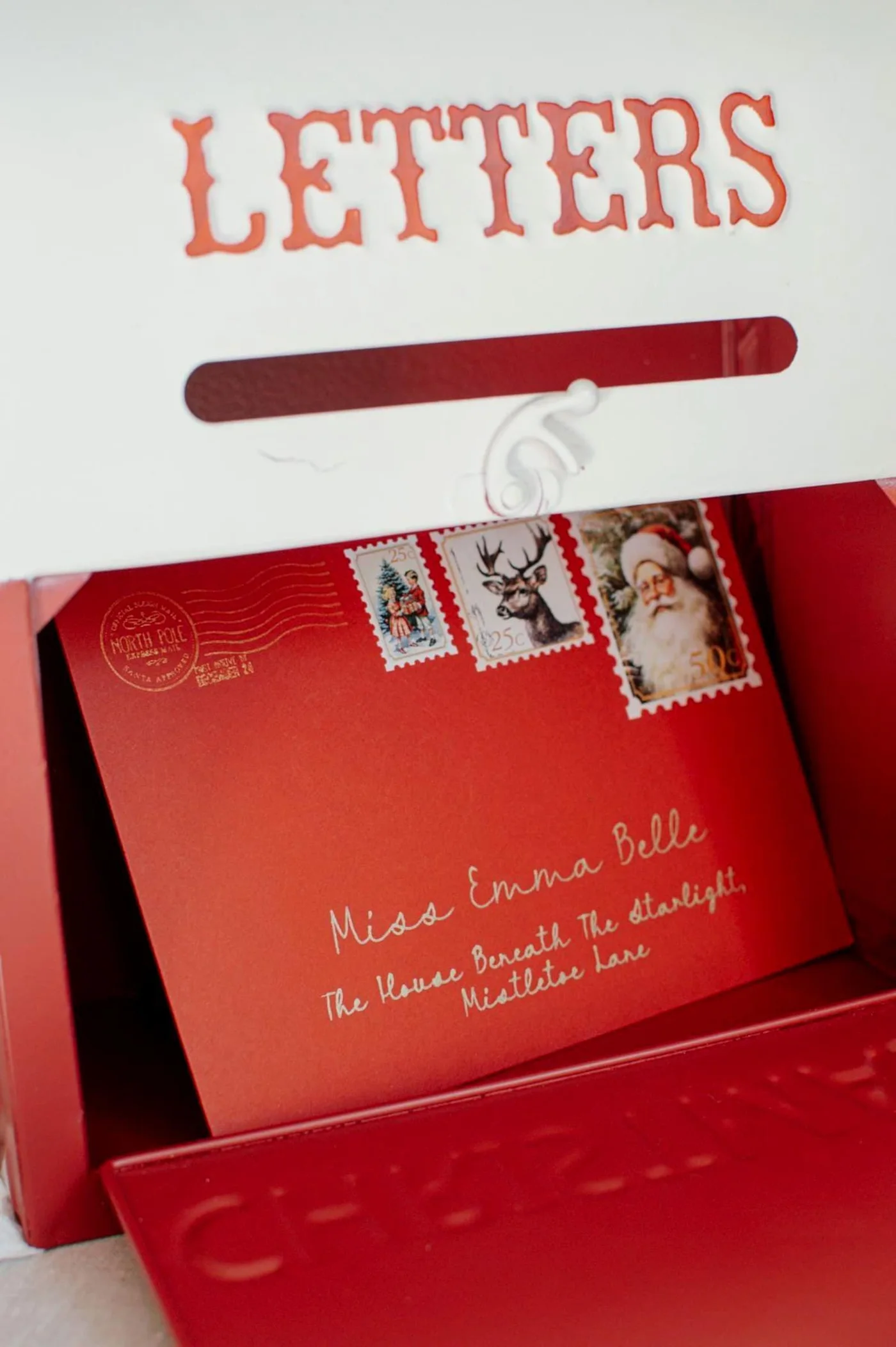 A red envelope with decorative stamps inside a festive Letters postbox