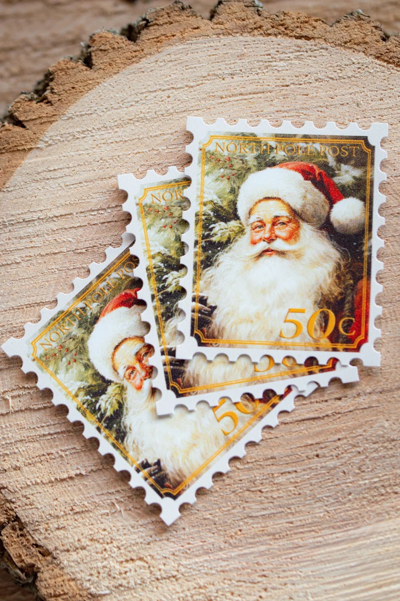 Decorative Santa portrait stamps with scalloped edges on a wooden slice